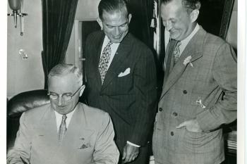 Man  signing Act with two men watching