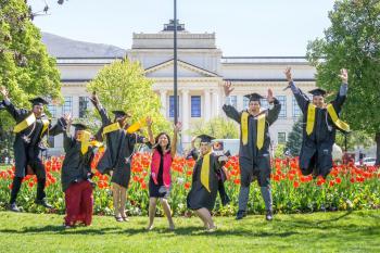 Group of Graduating students jumping in their caps and gowns